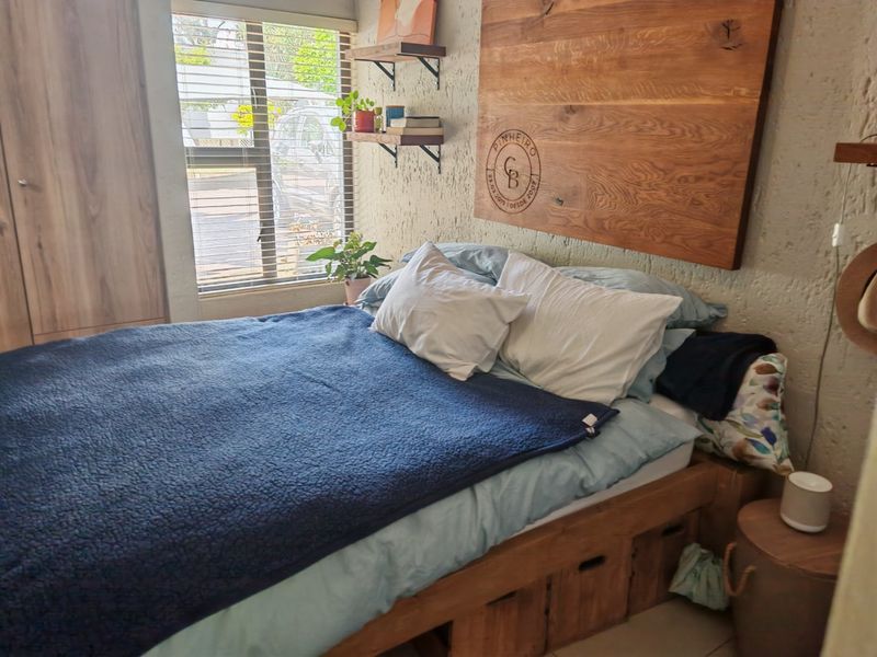 A cozy bedroom featuring a textured wall finish, built-in wardrobe storage, and venetian blinds for natural light control.