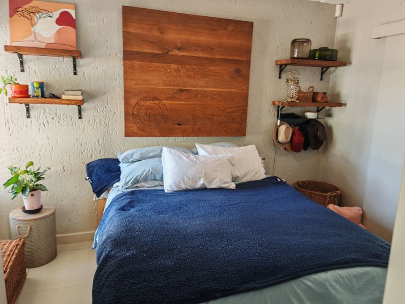 A cozy bedroom featuring textured walls, tiled flooring, and built-in wooden shelving units, providing a functional and rustic aesthetic.