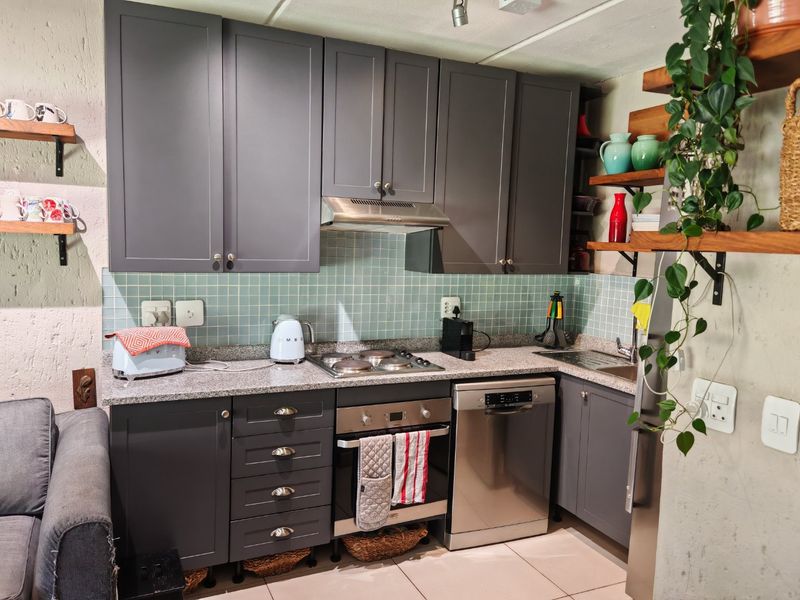 Modern kitchen featuring dark grey cabinetry, granite countertops, a tiled backsplash, and integrated stainless steel appliances including an oven, hob, and dishwasher.