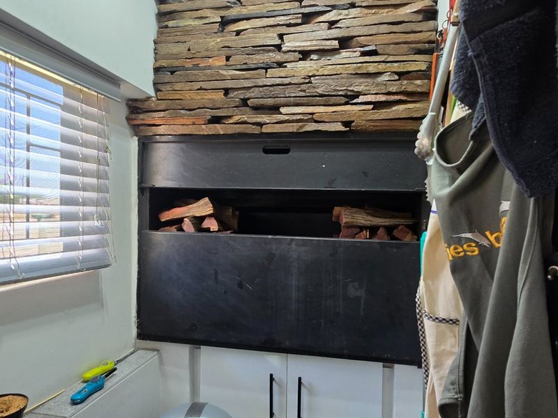Indoor entertainment area featuring a built-in braai with decorative stone cladding and fitted venetian blinds.