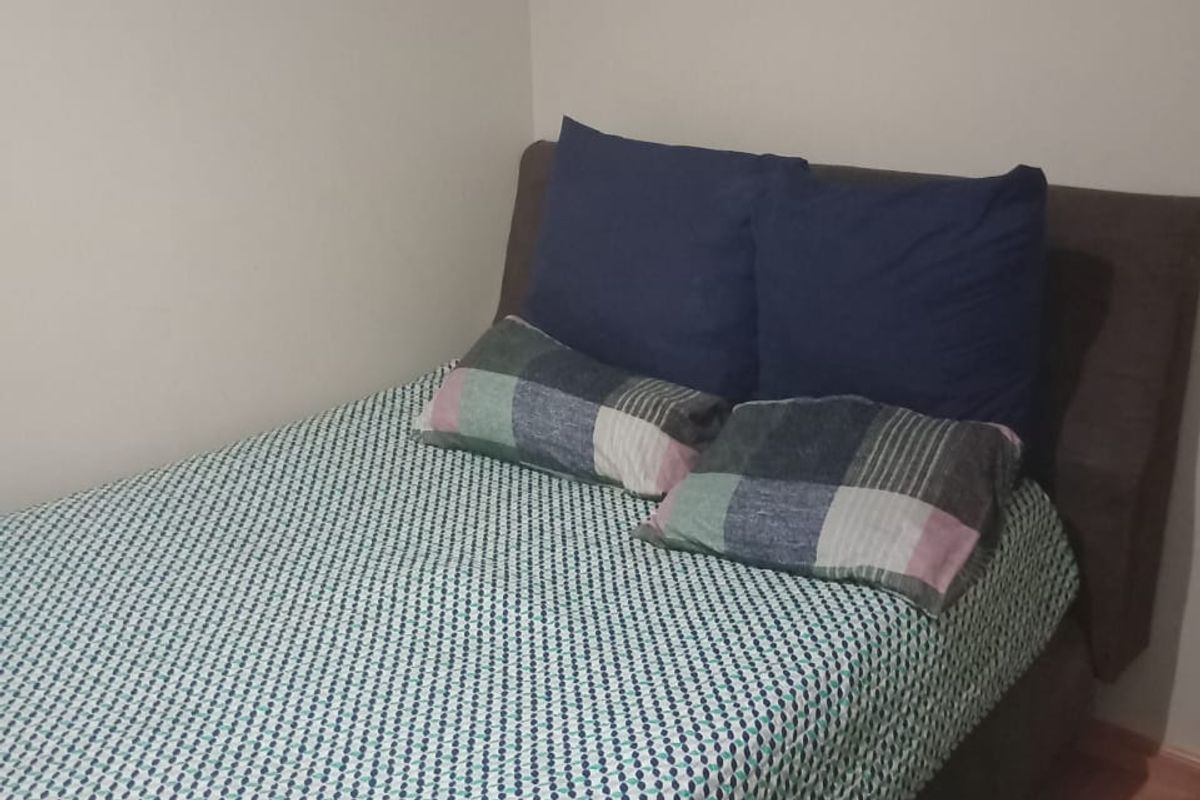 A compact bedroom featuring laminate flooring and neutral wall finishes, suitable for a guest room or home office setup.