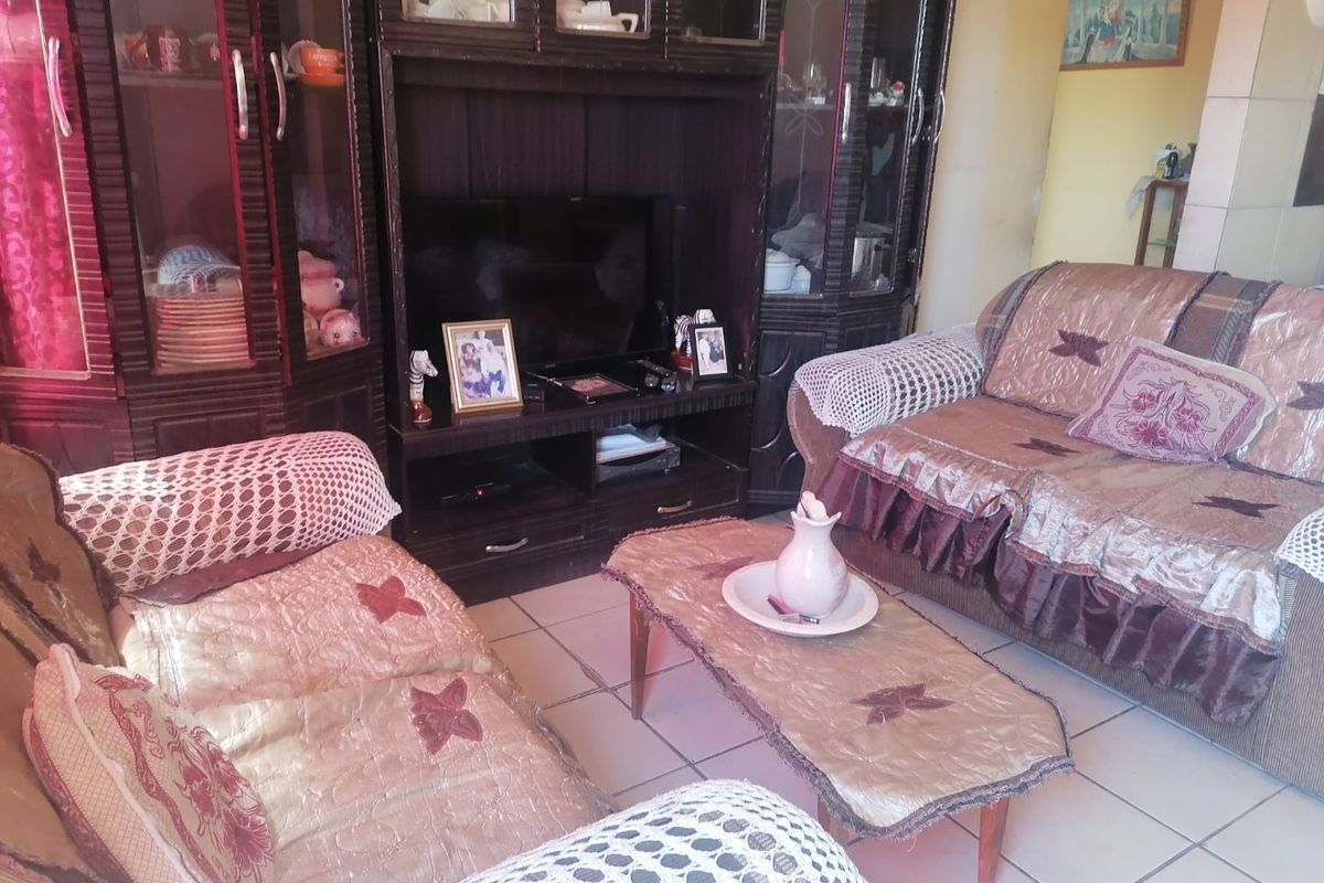 A living room area featuring ceramic floor tiles and a built-in dark wood cabinetry unit.