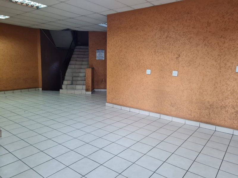 An empty, tiled hallway featuring a staircase and textured orange walls, providing a functional transition space within the apartment building.