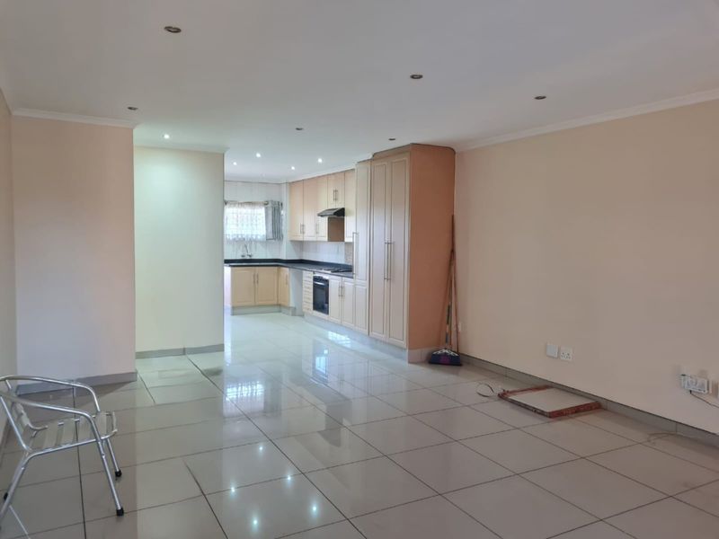 Spacious open-plan living area featuring tiled floors, recessed lighting, and a functional kitchen with built-in cabinetry, oven, and granite countertops.