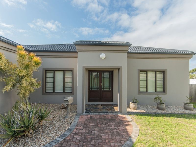 Front elevation of a modern house featuring a paved walkway leading to a double front door, tiled roof, and well-maintained exterior finishes.