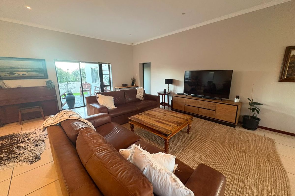 Spacious living room featuring tiled flooring, recessed lighting, and large sliding glass doors providing access to the outdoor patio area.