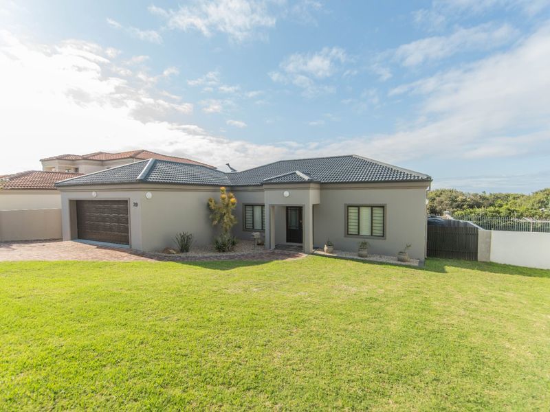 A well-maintained single-story residential home featuring a tiled roof, paved driveway, and an integrated double garage set on a spacious lawn.