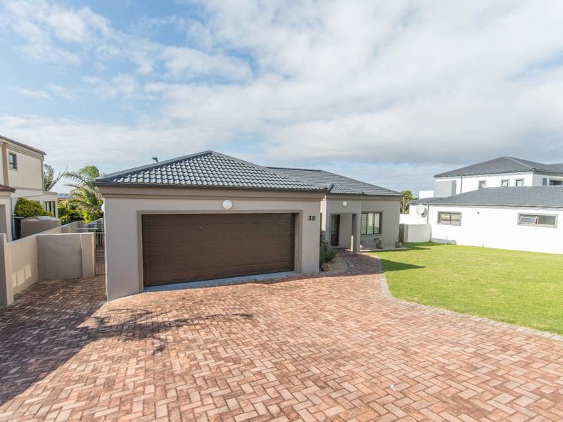 Front view of a modern house featuring a paved driveway, double garage, and a well-maintained lawn.