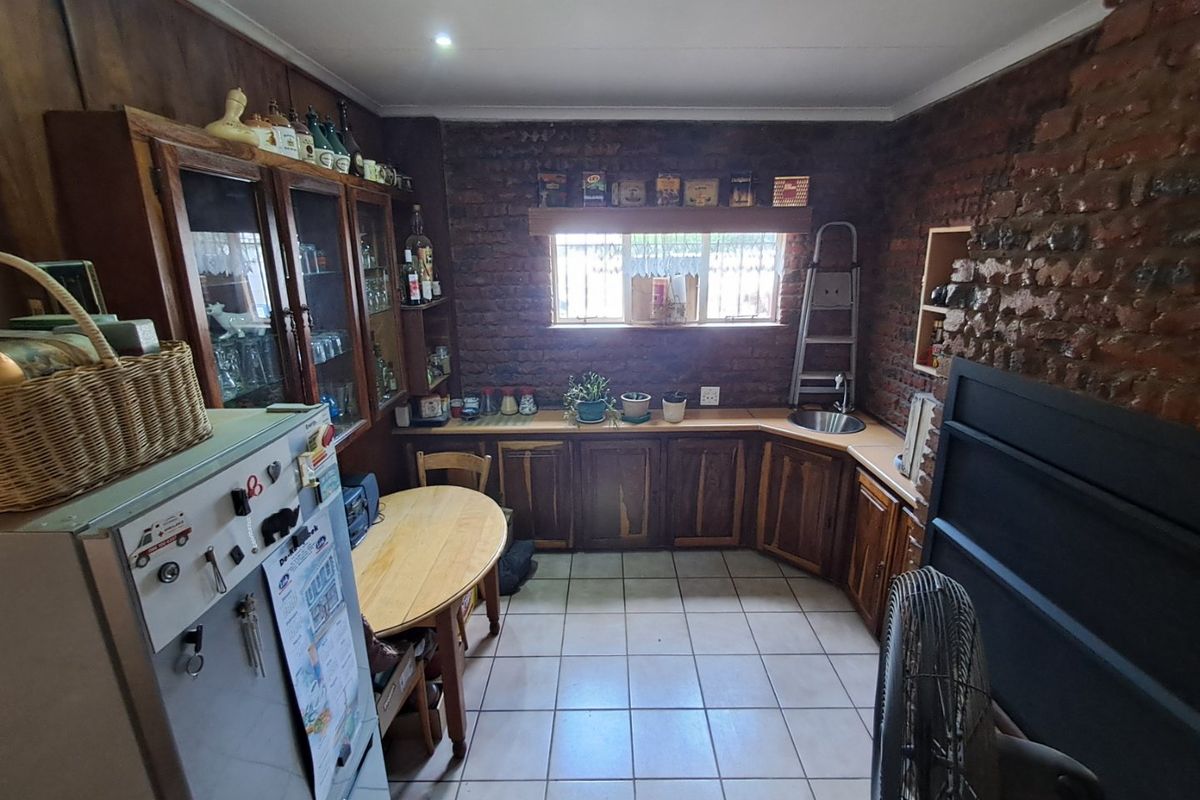 A rustic kitchen featuring exposed brick walls, tiled flooring, and traditional wooden cabinetry with an integrated sink area.
