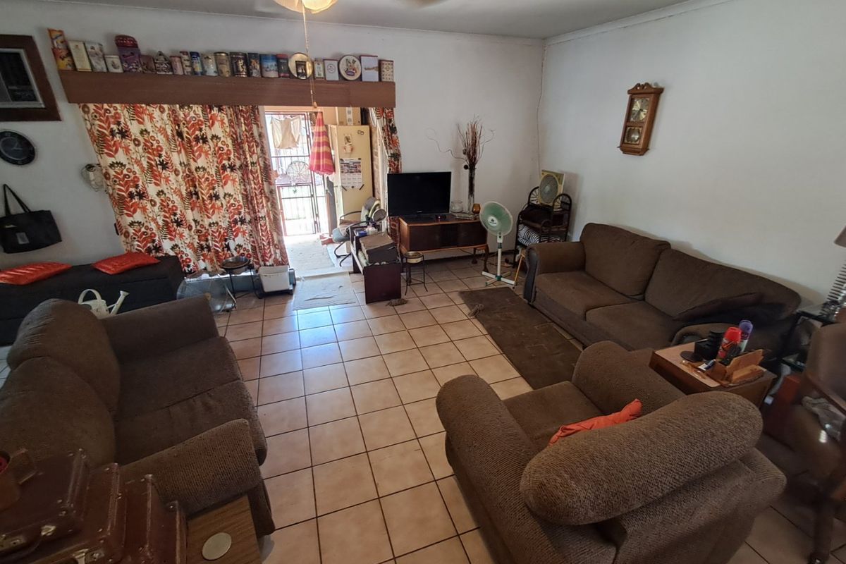 A spacious living room featuring ceramic tile flooring, a ceiling fan, and direct access to the exterior through a sliding glass door.
