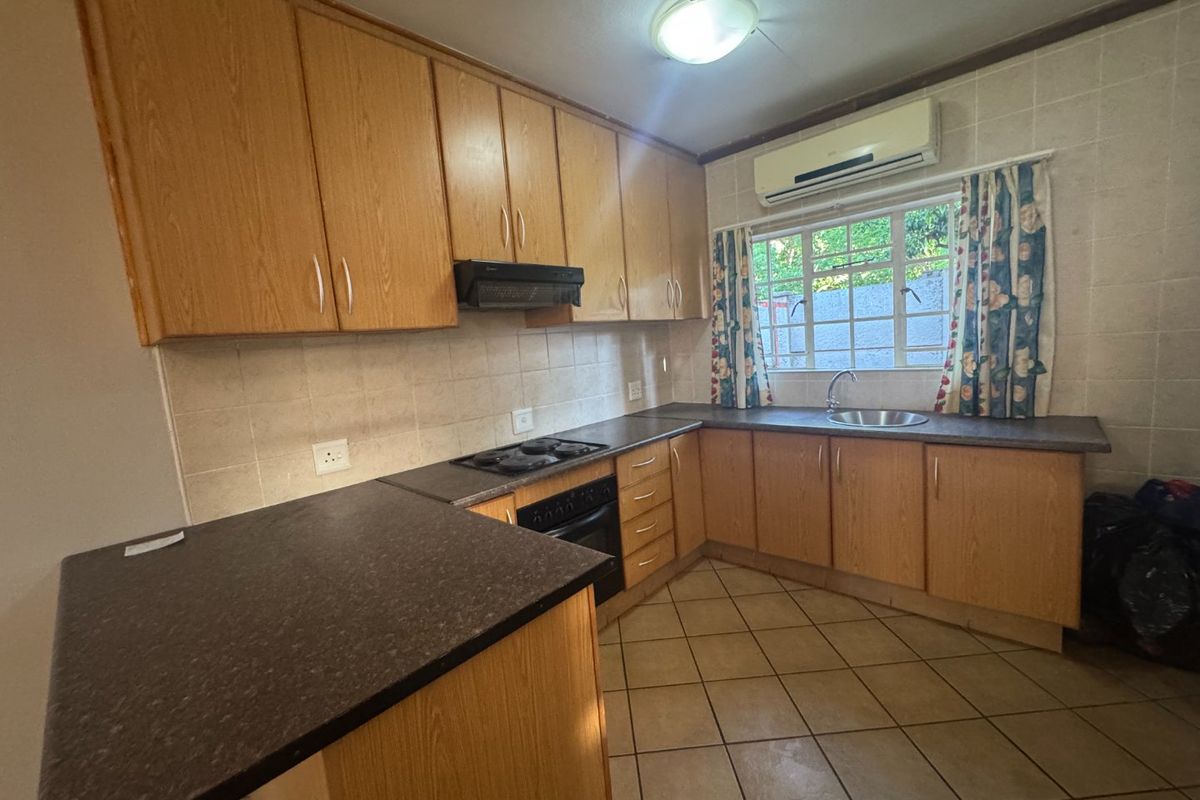 Functional kitchen featuring laminate cabinetry, built-in oven with hob, extractor fan, and tiled finishes, offering a practical layout for daily meal preparation.