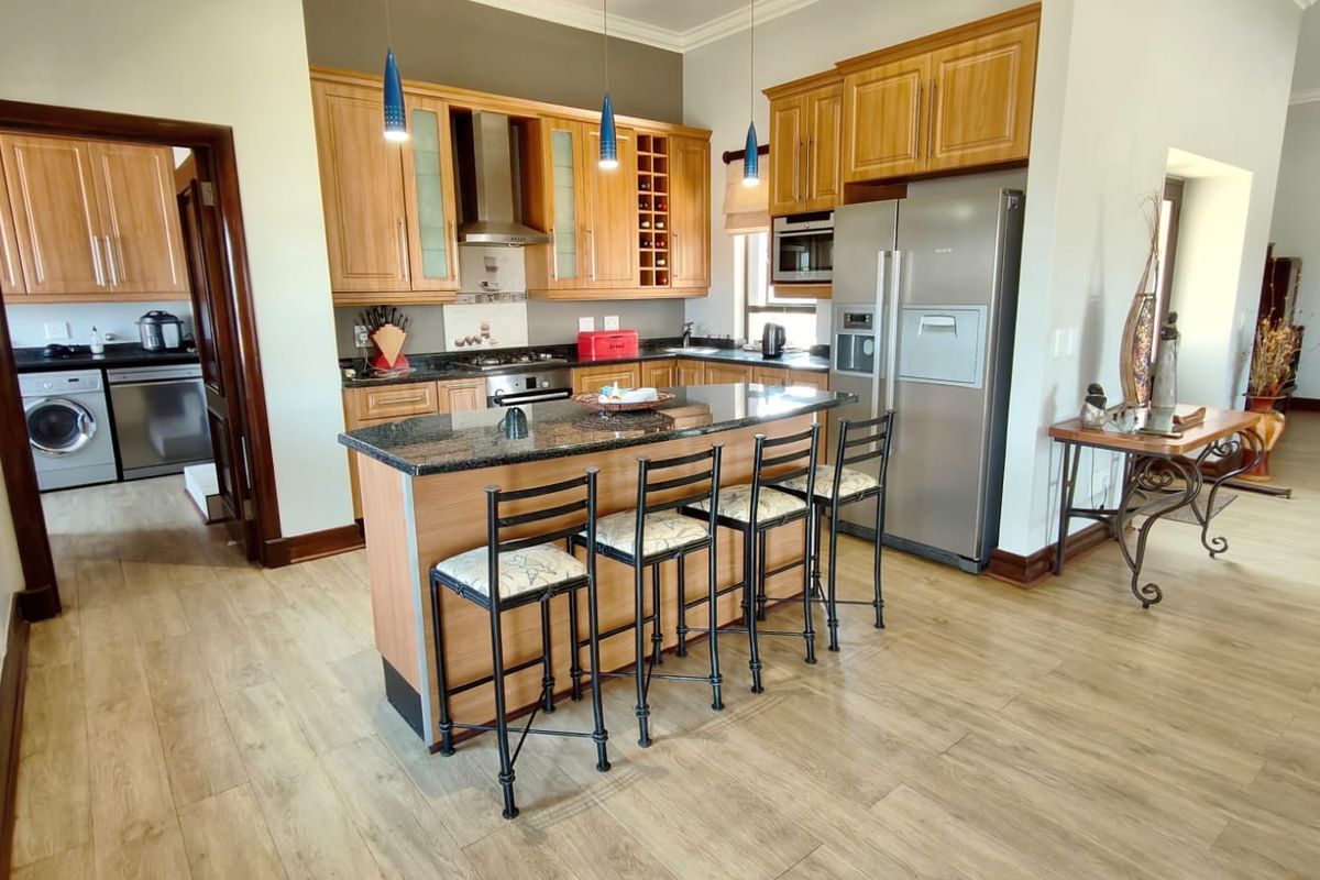 A functional kitchen featuring wooden cabinetry, granite countertops, a central island with breakfast bar seating, and integrated appliances.