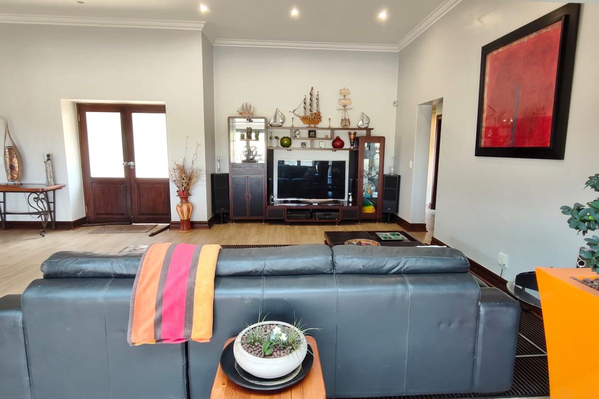 Spacious living room featuring laminate flooring, recessed downlighting, decorative coving, and double wooden doors leading to an adjacent area.