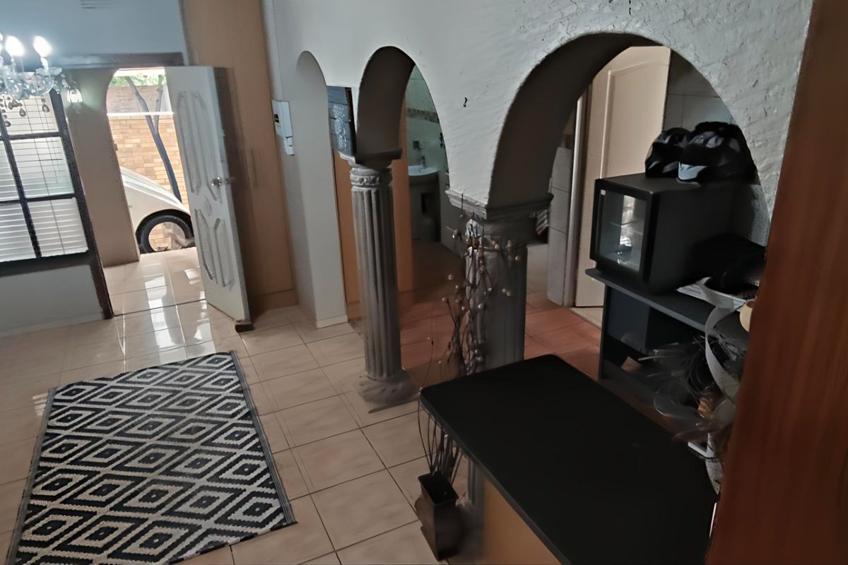 Living area featuring distinctive arched architectural dividers, decorative columns, tiled flooring, and a crystal chandelier, providing access to the exterior.