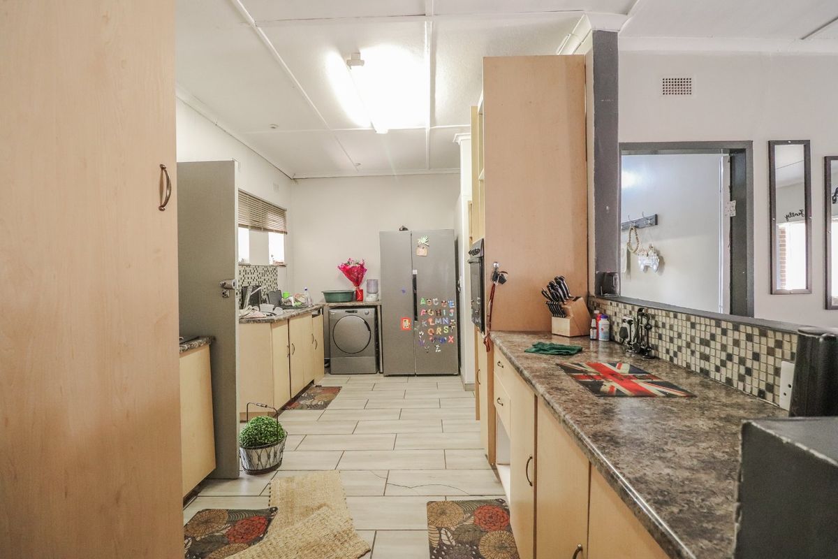 Functional kitchen featuring built-in cabinetry, mosaic tile backsplash, and tiled flooring, offering a practical layout with ample storage and workspace.