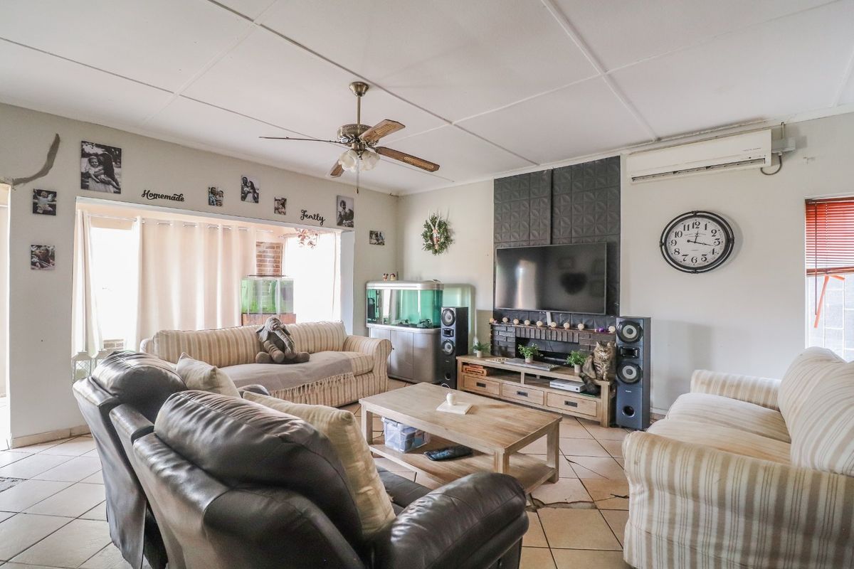 Spacious living room featuring tiled flooring, a ceiling fan, split-system air conditioning, and a decorative feature wall with a brick fireplace surround.