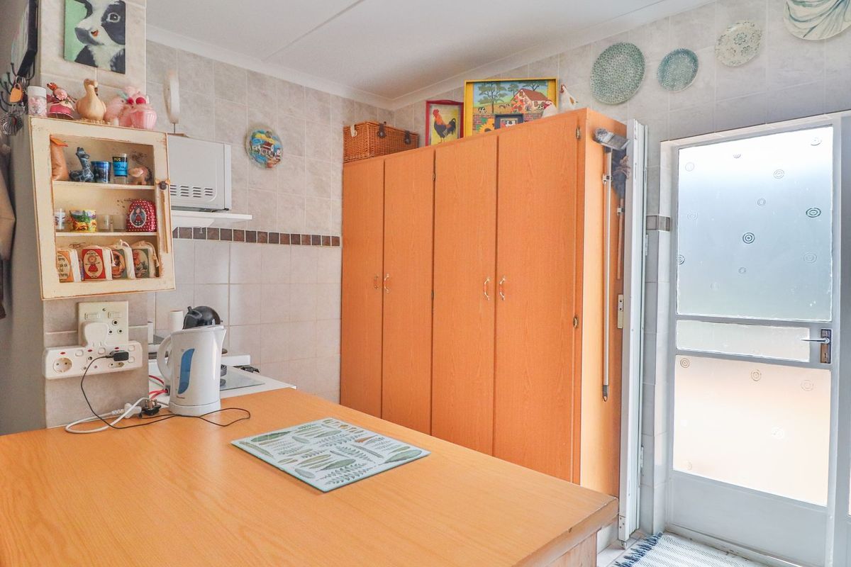 A functional kitchen area featuring built-in cabinetry, tiled wall finishes, and direct access to the exterior via a glass panel door.