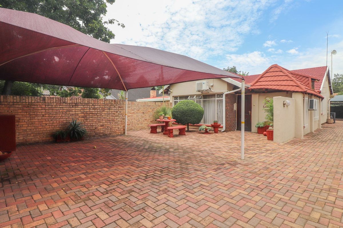 A paved rear courtyard area featuring a large shade sail, brick boundary walls, and direct access to the main dwelling.