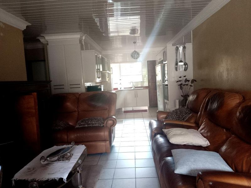 Open plan living and kitchen area featuring tiled floors, glossy ceiling panels, and built-in kitchen cabinetry.
