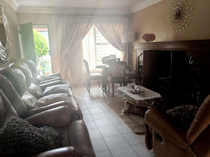 A living room featuring tiled flooring and a sliding door providing access to the exterior, with natural light entering through the window.