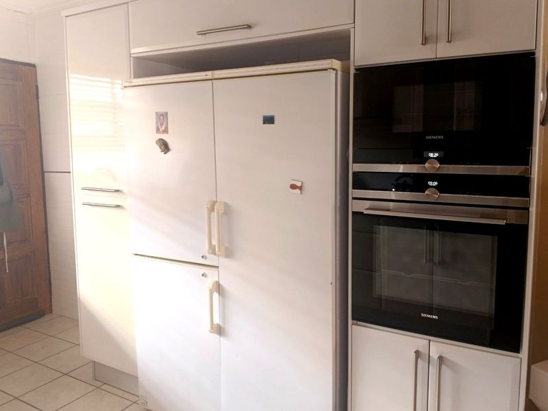 A modern kitchen featuring white cabinetry, integrated Siemens oven and microwave, and tiled flooring.