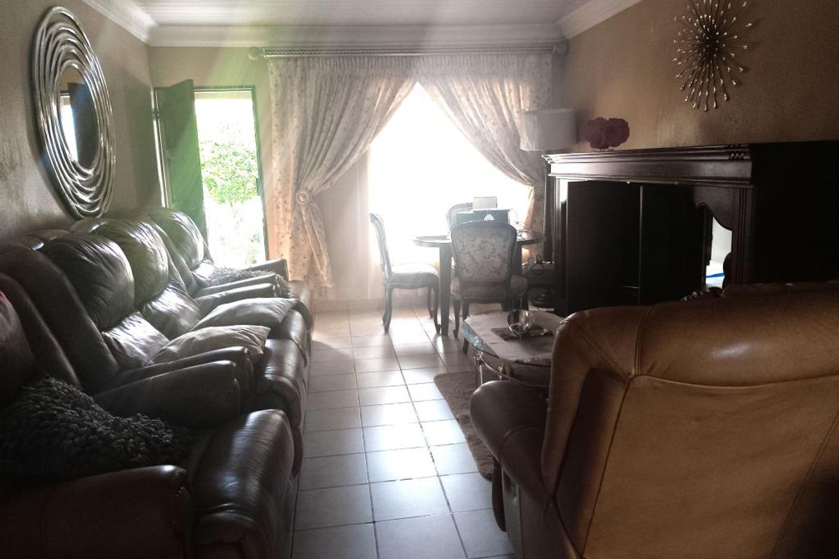 A living room featuring tiled flooring, crown molding, and a sliding glass door providing access to the exterior.