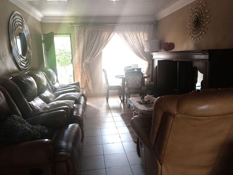 A living room featuring tiled flooring, crown molding, and a sliding glass door providing access to the exterior.