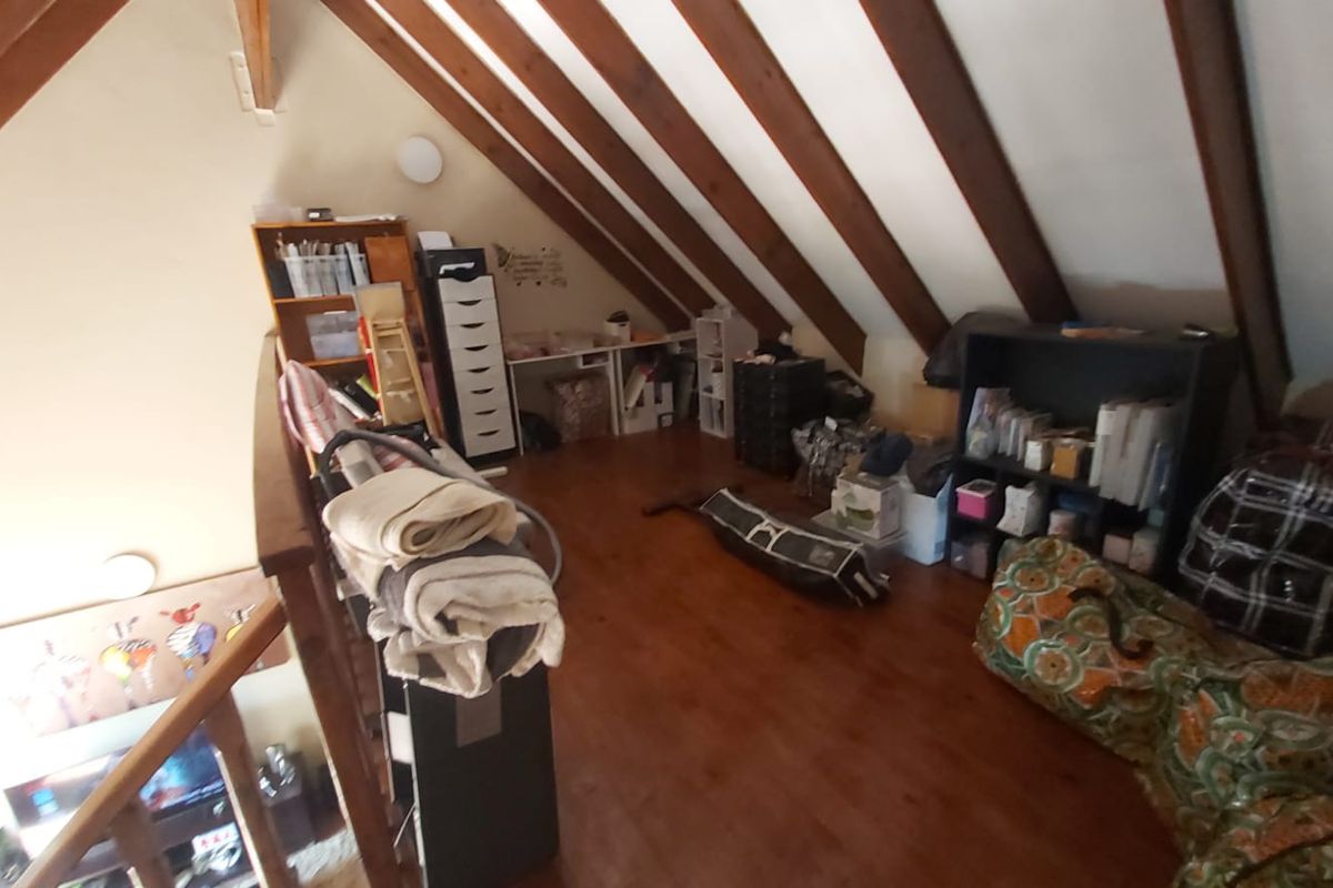 An attic-style loft space featuring exposed timber roof beams and wooden flooring, currently utilized as a storage and hobby area.