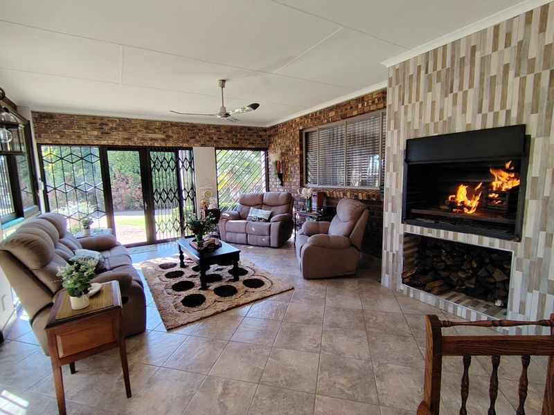 Spacious living room featuring a built-in fireplace, exposed brick walls, tiled flooring, and large sliding doors providing access to the garden.