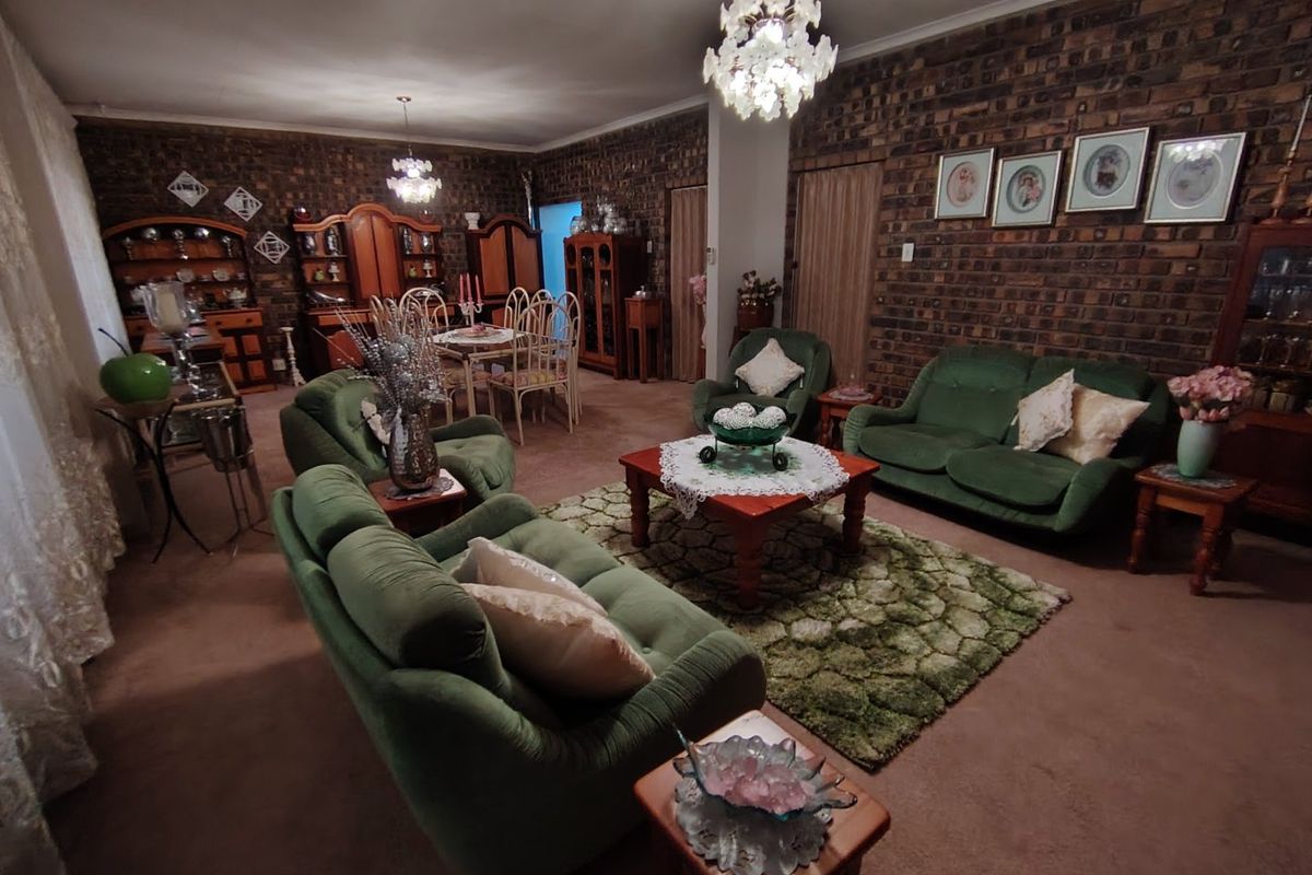 Spacious living area featuring exposed brick walls and decorative chandeliers, offering a traditional aesthetic with potential for modern updates.
