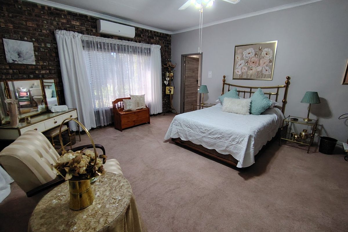 Spacious bedroom featuring an exposed brick accent wall, carpeted flooring, and a split-system air conditioner for climate control.