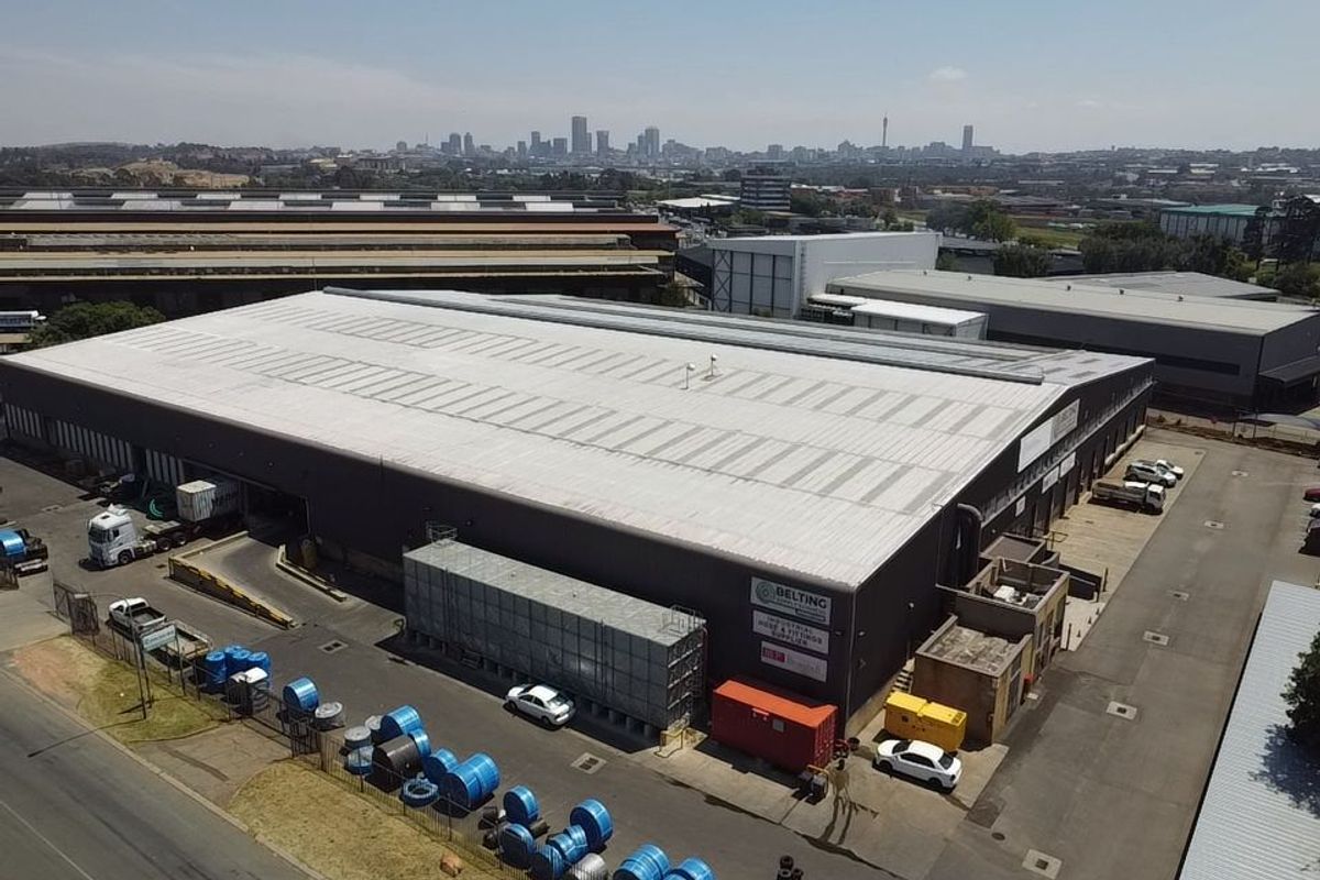 Aerial view of a large industrial warehouse facility featuring a metal roof, loading bays, and an expansive paved yard area.