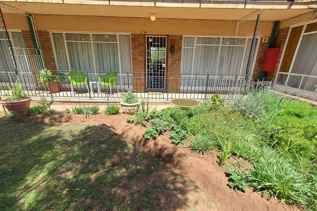 Ground floor apartment exterior featuring a private garden area, security gate, and access to the living space through sliding glass doors.