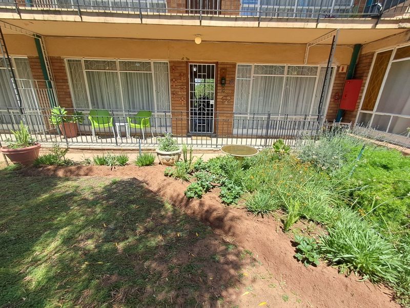 Ground floor apartment exterior featuring a private garden area, security gate, and access to the living space through sliding glass doors.