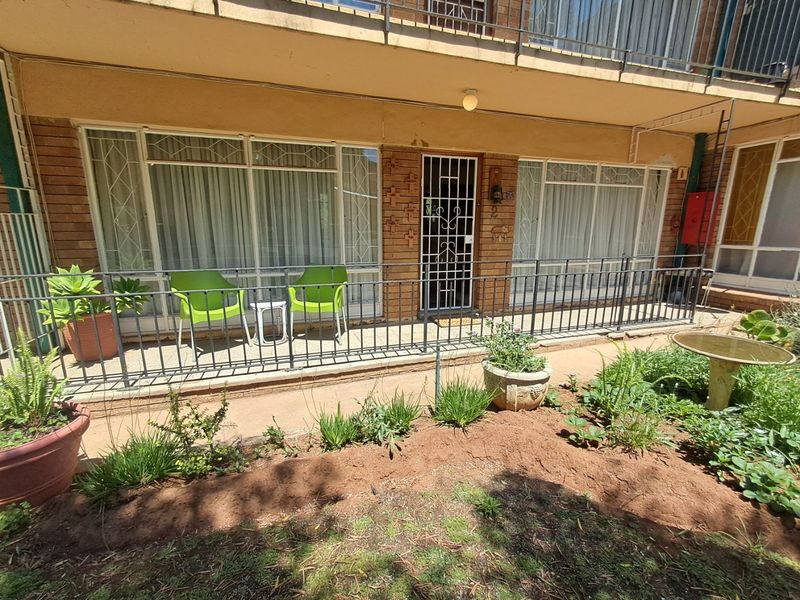 Ground floor apartment patio featuring a brick facade, metal security gate, and large glass sliding doors leading into the living area.