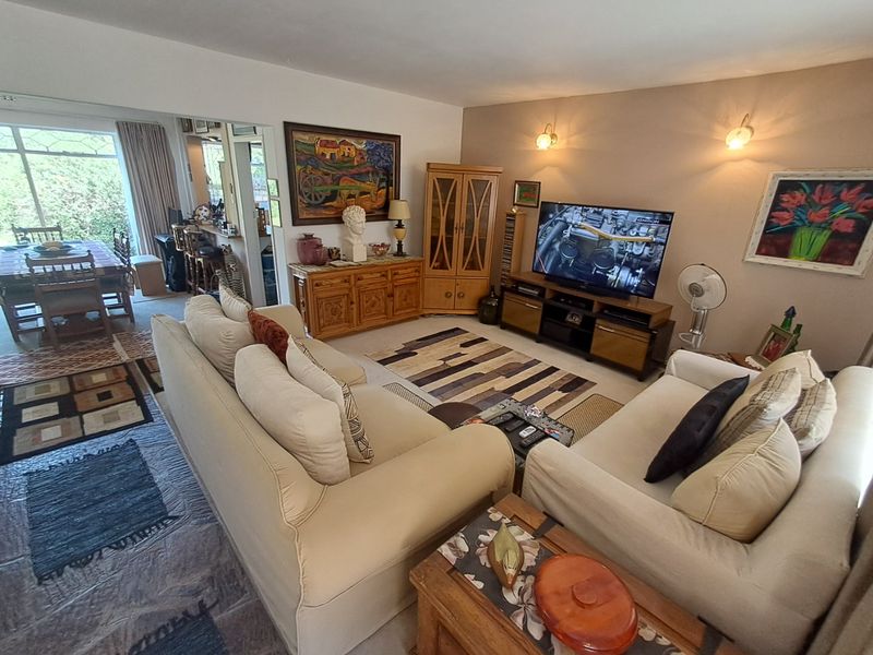 Open plan living and dining area featuring tiled flooring, wall-mounted lighting, and a large sliding glass door providing access to the outdoor space.