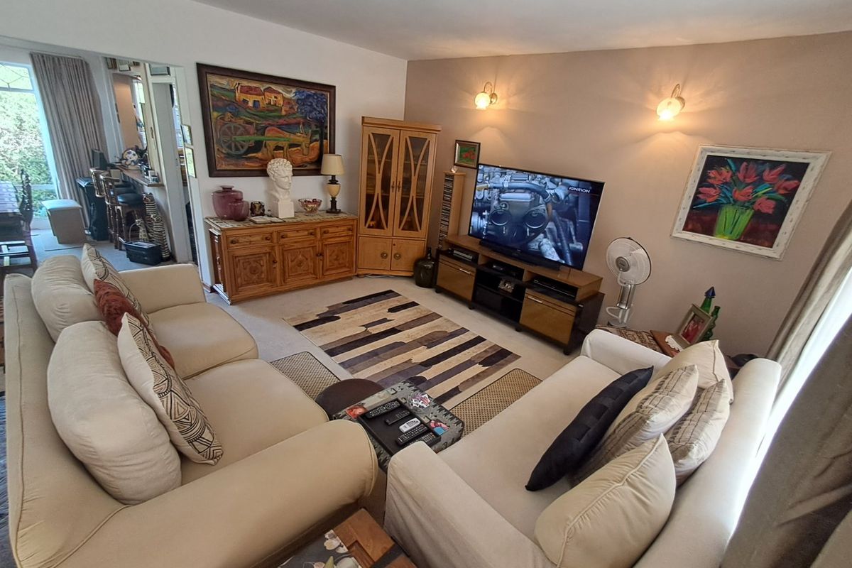 A comfortable living room featuring carpeted flooring and wall-mounted lighting fixtures, providing a warm and inviting space for relaxation.