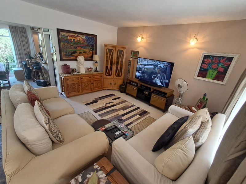 A comfortable living room featuring carpeted flooring and wall-mounted lighting fixtures, providing a warm and inviting space for relaxation.