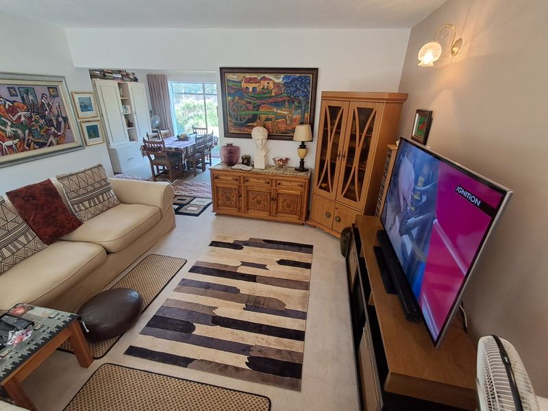 An open-plan living and dining area featuring neutral carpeting, built-in storage cabinetry, and a sliding glass door providing access to the outdoor space.