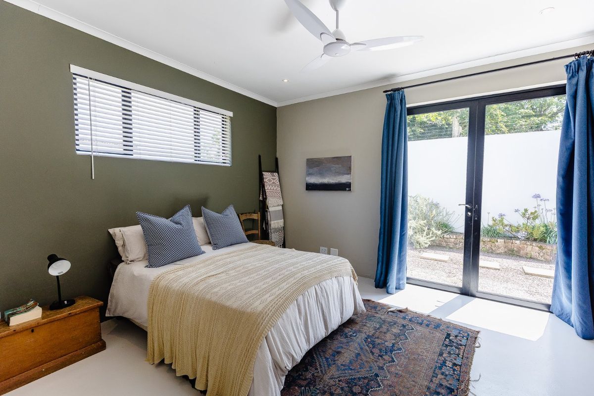 A well-lit bedroom featuring a ceiling fan, modern recessed lighting, and double glass doors providing direct access to the rear garden area.