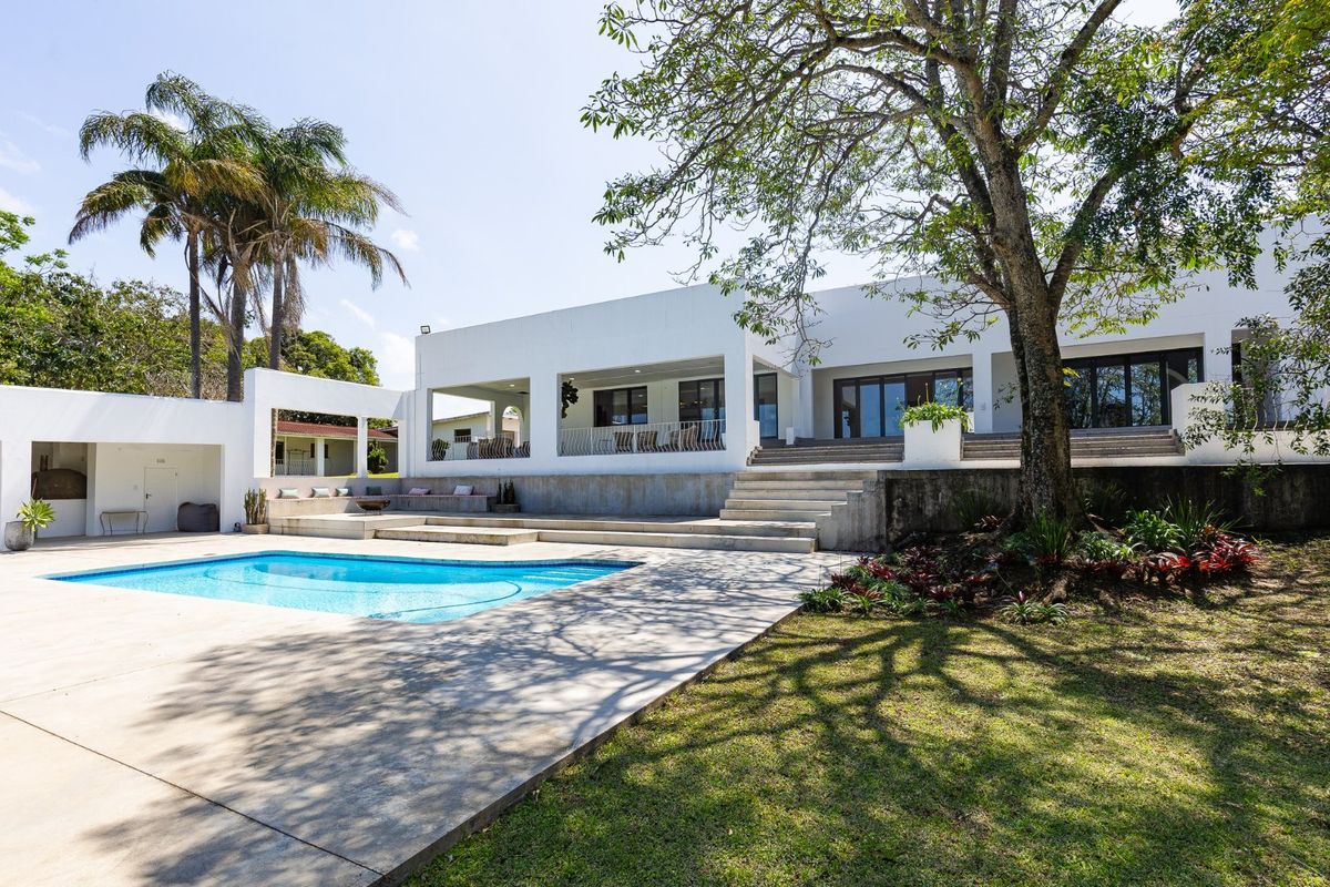 Spacious rear exterior featuring a swimming pool, expansive concrete patio, covered terrace, and tiered concrete steps leading to the main residence.
