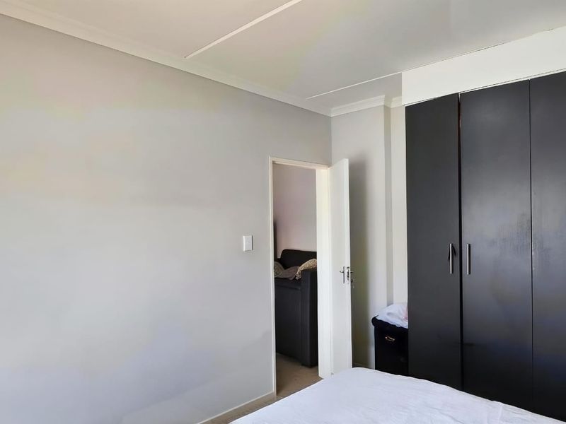 A bedroom featuring neutral wall finishes and a dark built-in wardrobe, providing functional storage space within the room.
