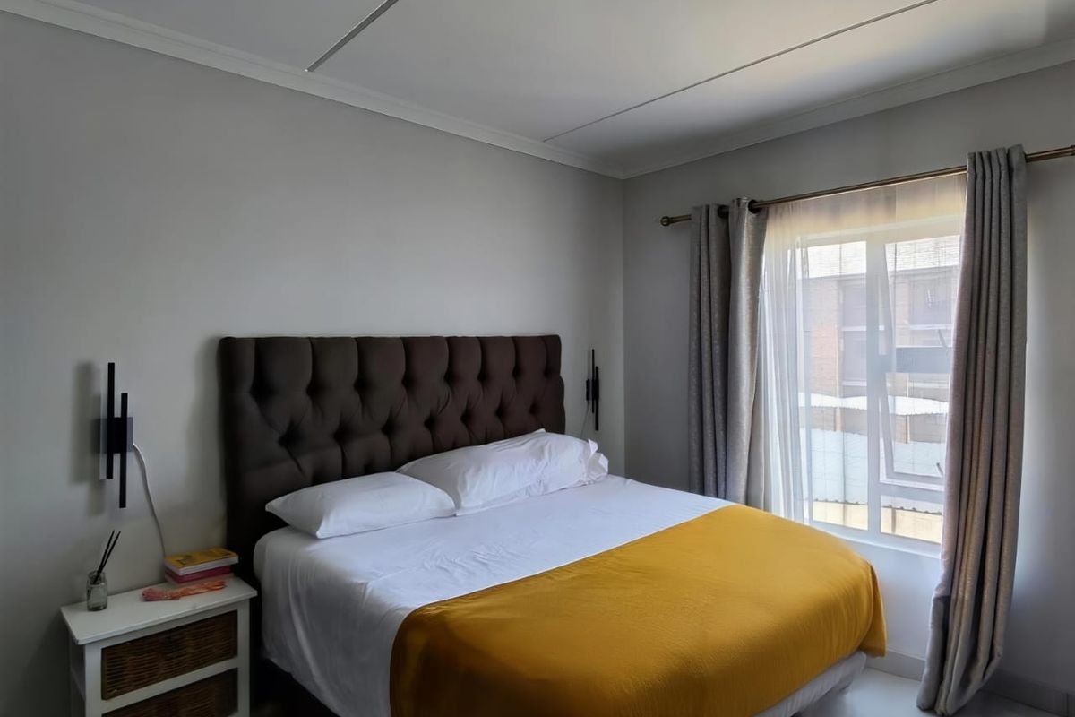 A well-lit bedroom featuring neutral walls, a window with curtain treatments, and coving detail.