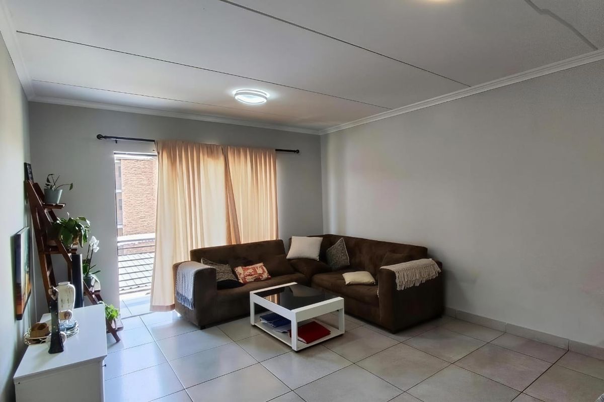 A functional living room featuring tiled flooring, neutral wall finishes, and a sliding glass door providing access to an outdoor area.