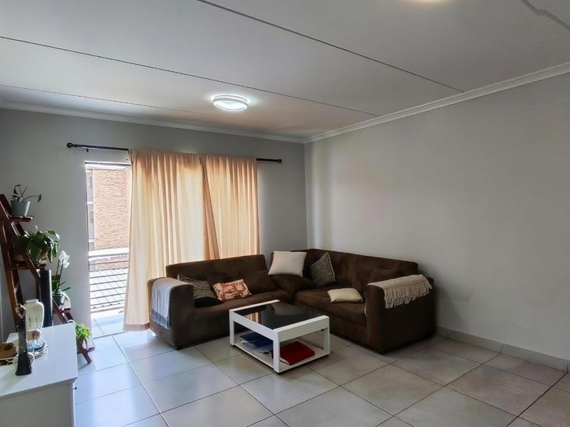 A functional living room featuring tiled flooring, neutral wall finishes, and a sliding glass door providing access to an outdoor area.