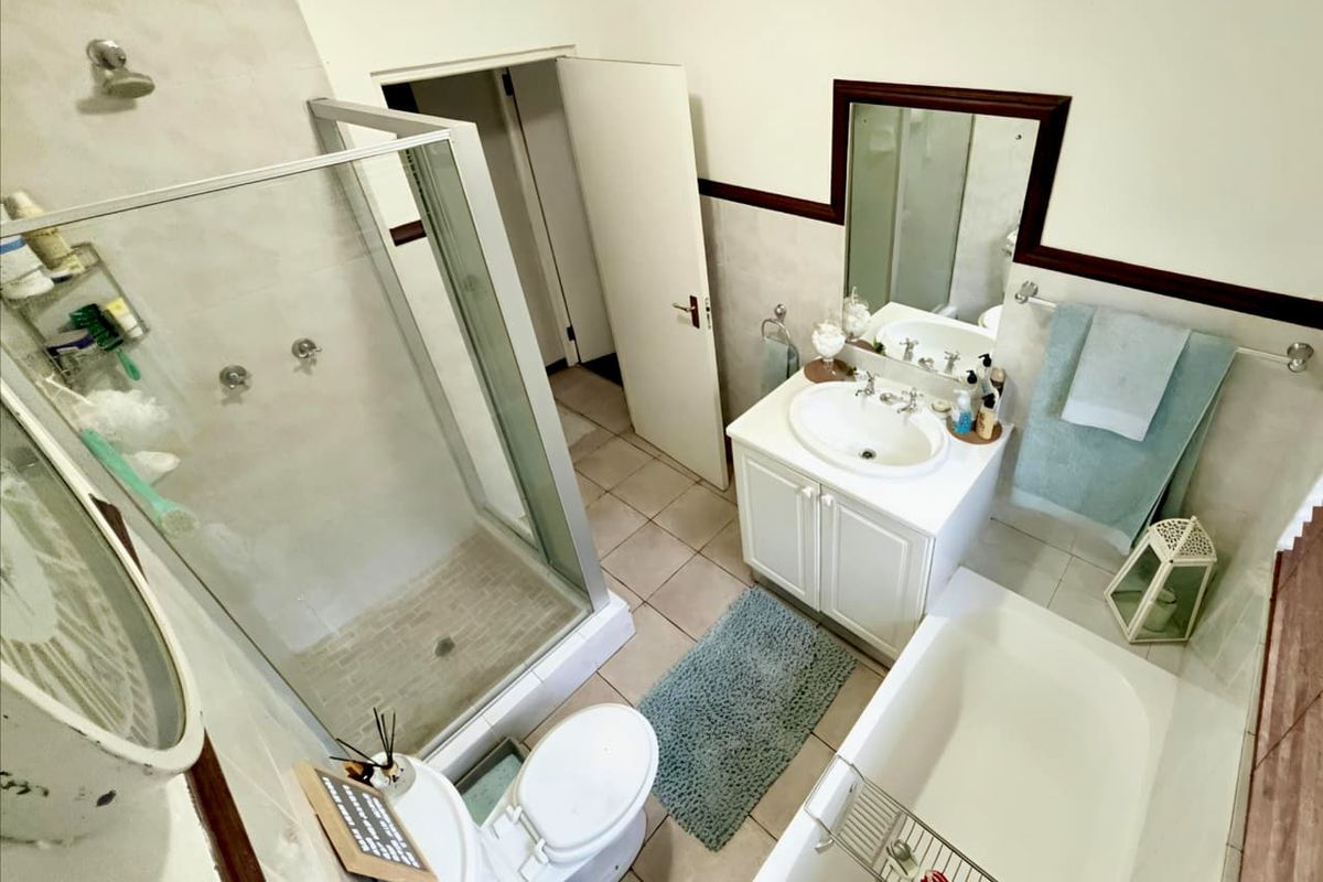 A functional bathroom featuring a glass-enclosed shower, a separate bathtub, a vanity with a basin, and tiled flooring.