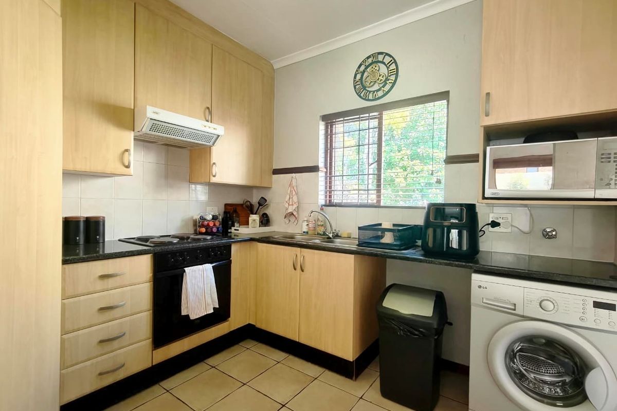 Functional kitchen featuring light wood cabinetry, dark granite countertops, built-in oven, extractor fan, and space for a front-loading washing machine.
