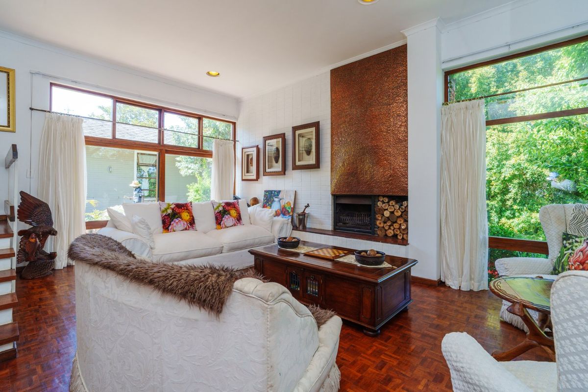 Bright living room featuring parquet flooring, large windows, and a distinctive copper-clad fireplace with built-in log storage.