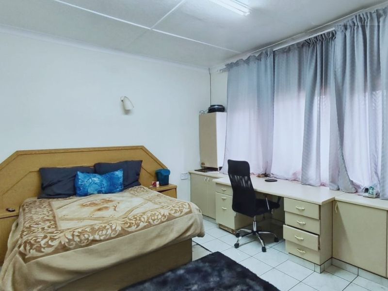 A bedroom featuring built-in cabinetry, a desk area, and tiled flooring, offering functional storage and workspace solutions.