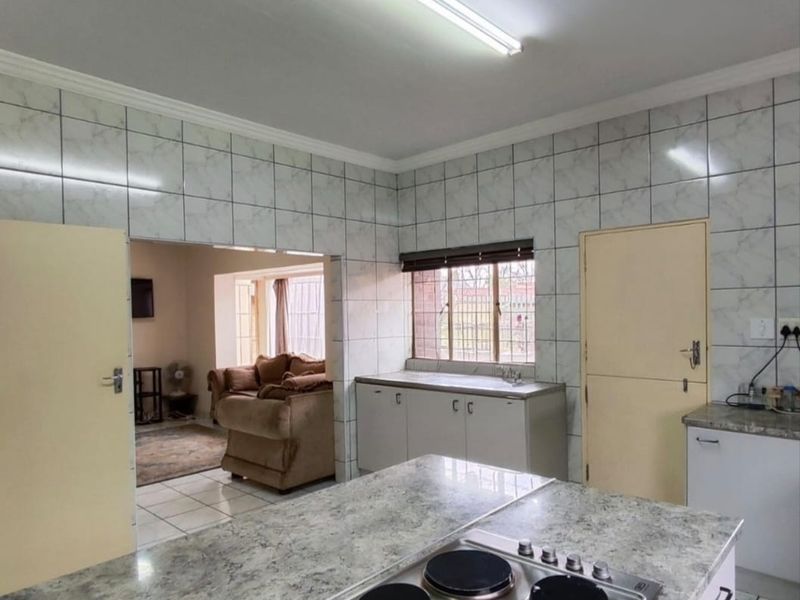 Open-plan kitchen area featuring built-in cabinetry, laminate countertops, and an integrated electric hob, flowing into the adjacent living space.